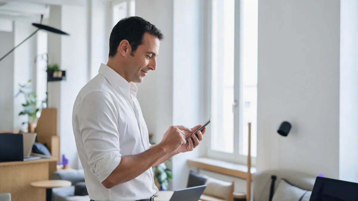 Un consulente risponde a un commento dallo smartphone vicino alla finestra del suo studio