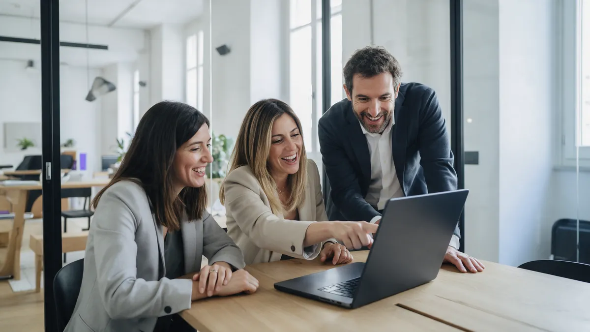 Un team marketing rivede insieme un post al portatile in sala riunioni